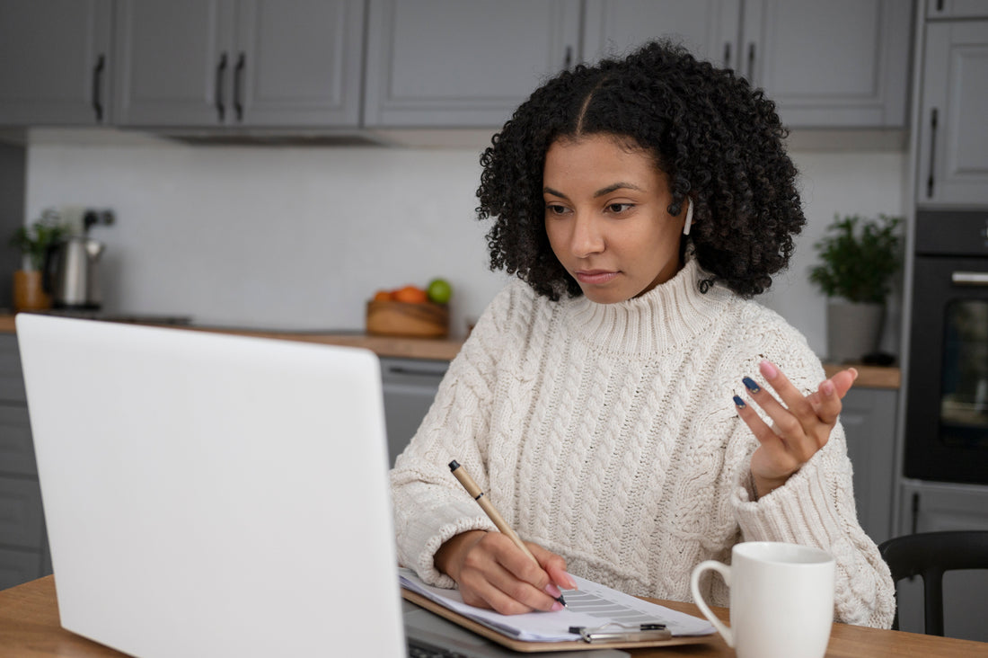 Black woman sitting at computer with pen and pencil.